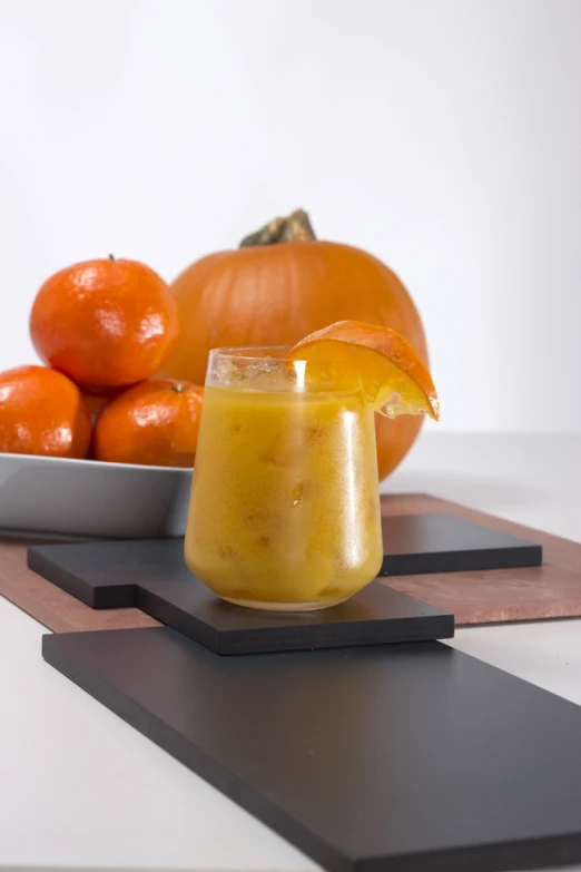 a small glass filled with liquid sits next to some fruits