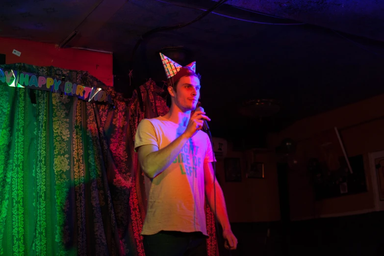 a man in white shirt holding microphone and looking into camera