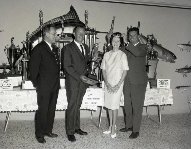 some people and a lady standing in front of trophies