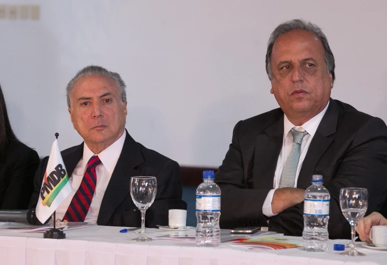 three people sitting at a table with three empty glasses