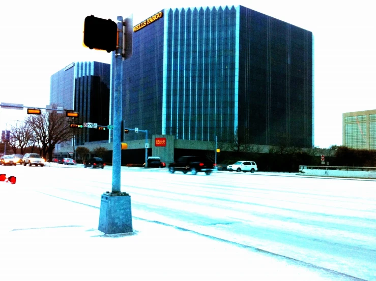 a stoplight and traffic sign on the corner of a snowy street