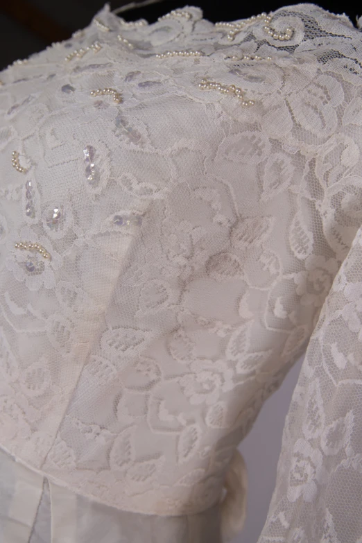 a white dress that is on display with lace