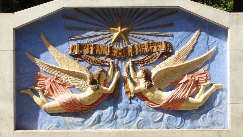 two ceramic statues of angels in front of a blue sign