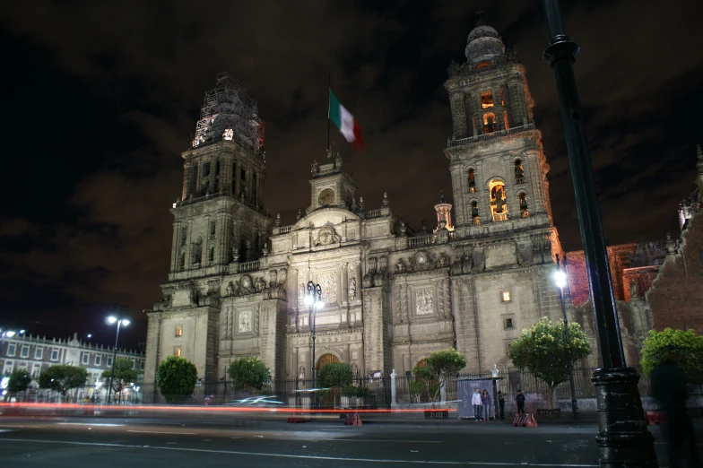 an old building is shown with lit up flags on top