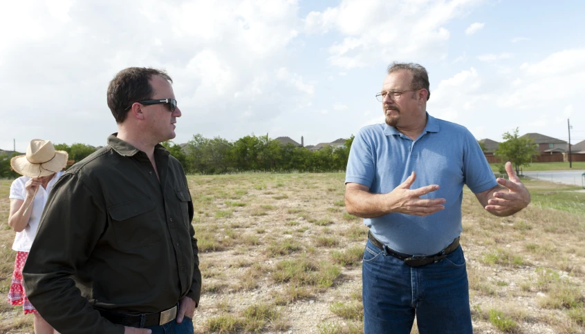 two men are talking outside in the grass