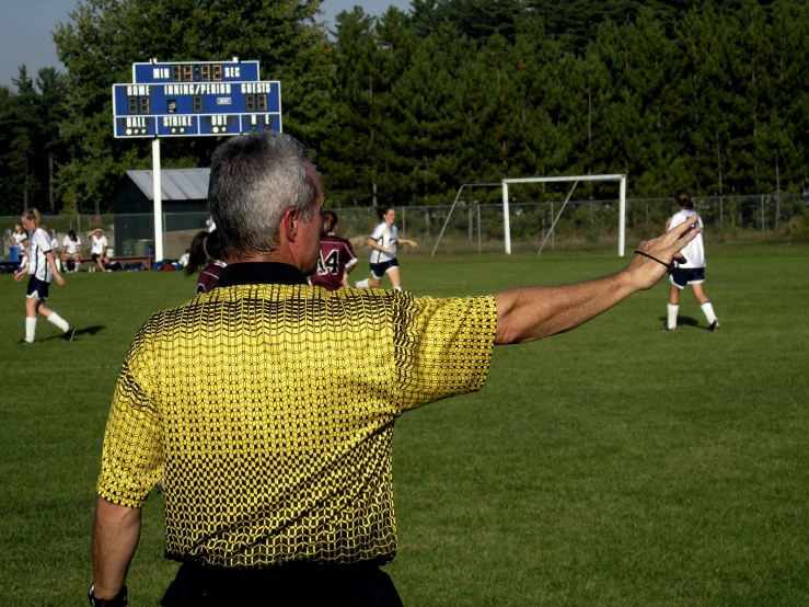 a man in a yellow shirt holds up his hands to control the ball during a soccer game