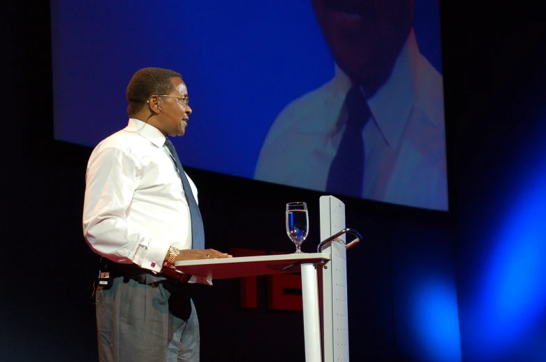 a man standing at a podium speaking to a crowd