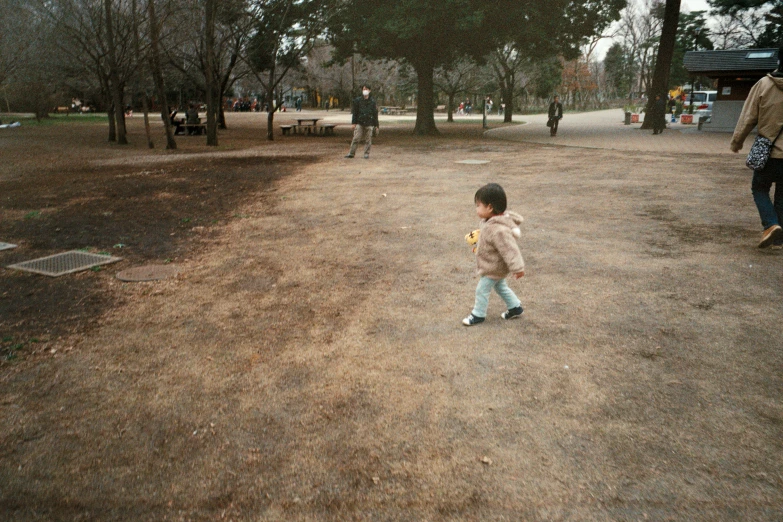 the little boy is standing outside near trees