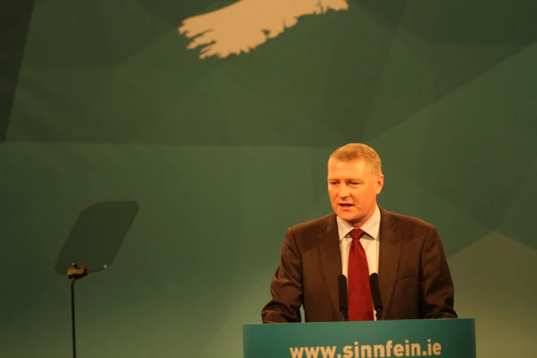 a man speaking into a microphone in front of a stage