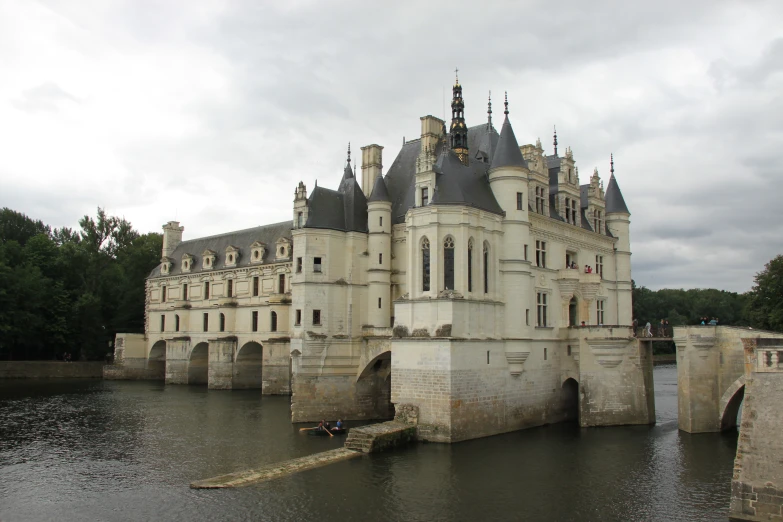 a very pretty castle surrounded by water in a park