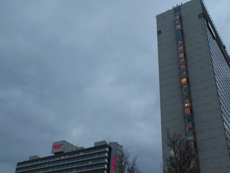 two buildings with lights all over them on a cloudy day