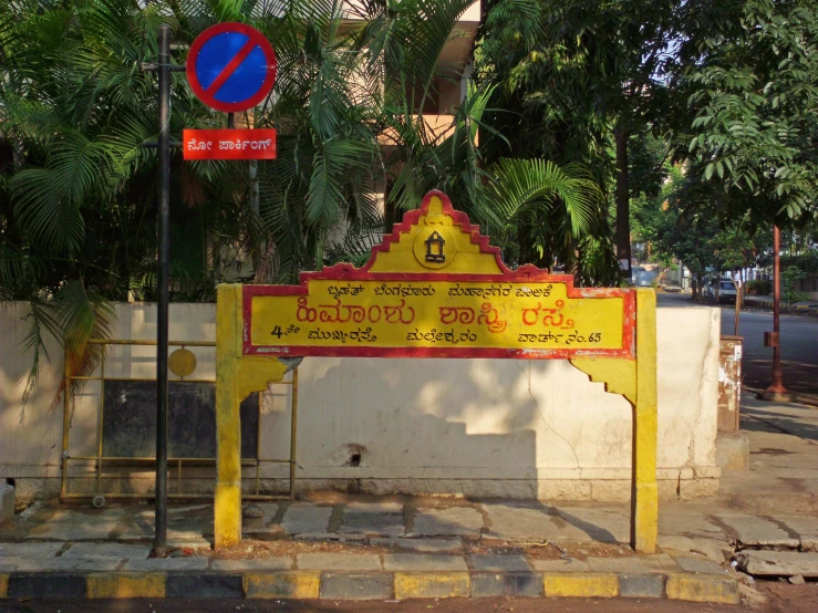a yellow sign sitting on top of a sidewalk next to a fence
