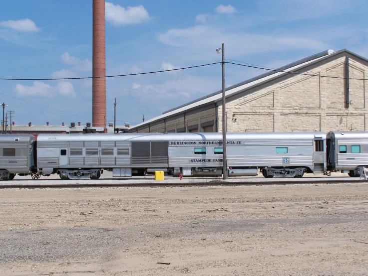 two silver colored travel trailers sit outside of an industrial building