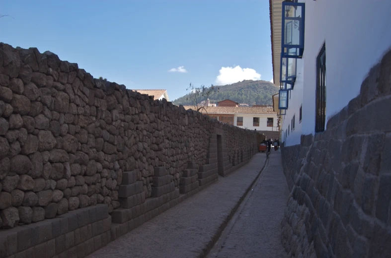 a street that has stone walls and houses behind it