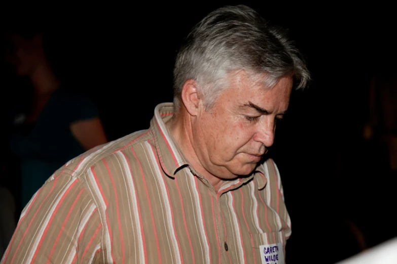 a man with white hair and wearing a shirt looks down