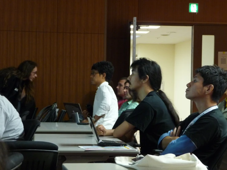 a group of people sitting at a table with laptop computers