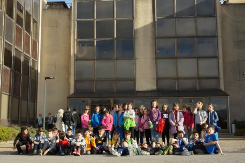 a group of children standing next to each other in front of a building