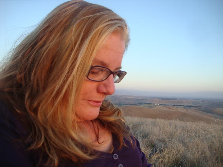 a woman standing on top of a hill near a field