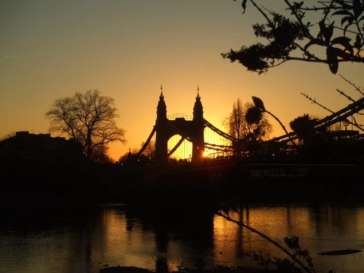 a bridge with the sun behind it over water