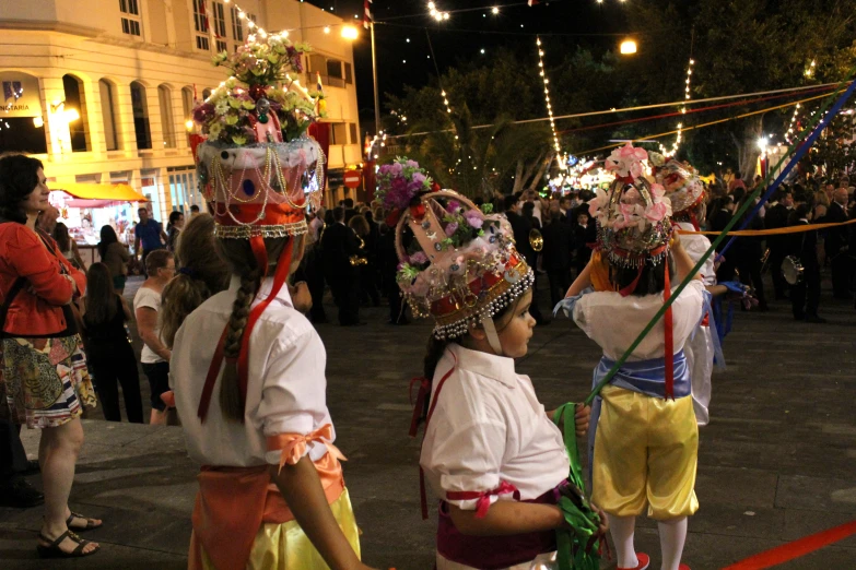 people standing on a street at night wearing headgear