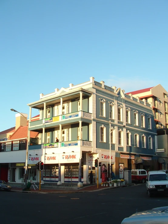 an older building sits on the corner with lots of parked cars