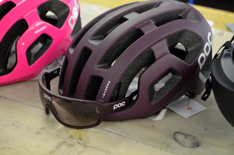 helmets, sunglasses and a helmet sitting on top of a wooden surface