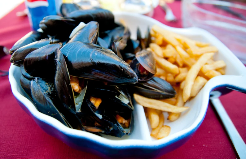 a bowl filled with mussels and fries