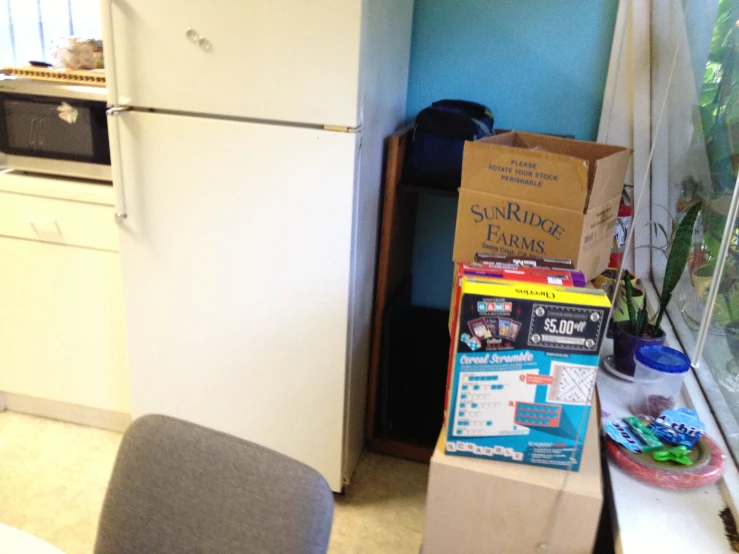 refrigerator next to table with boxes on it in a kitchen