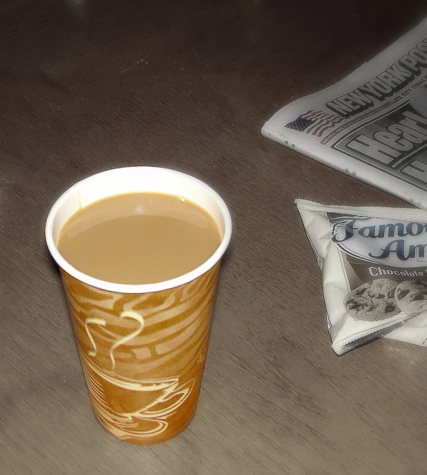 a brown cup next to three cookies on the table