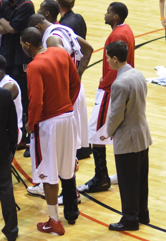 the men are standing around the basketball court talking to each other