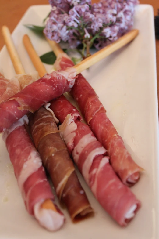 a plate with some meat wrapped around sticks