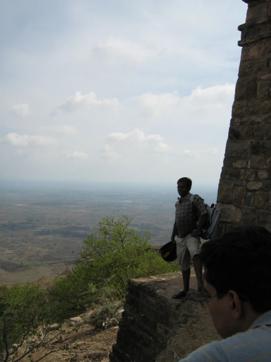 people standing on a stone wall next to a field