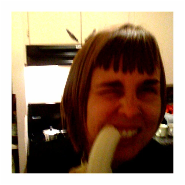 there is a woman smiling and eating a banana