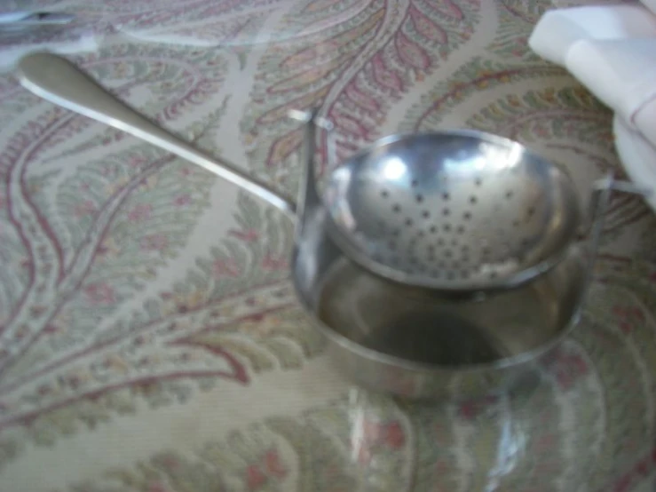 a metal bowl on a bed holding a ladle