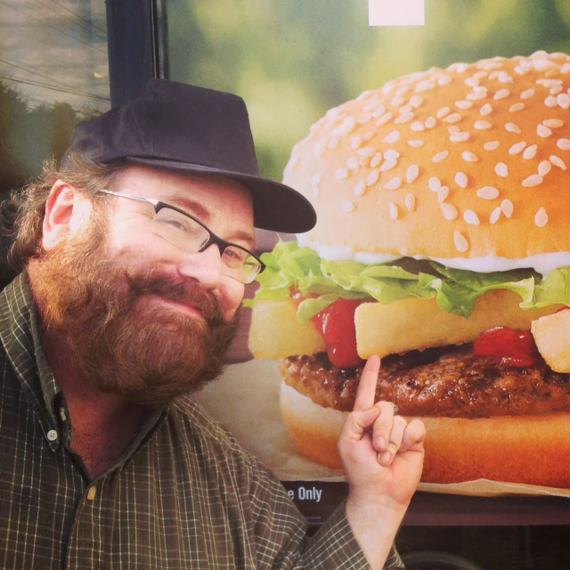 a man giving the middle finger sign with a big burger