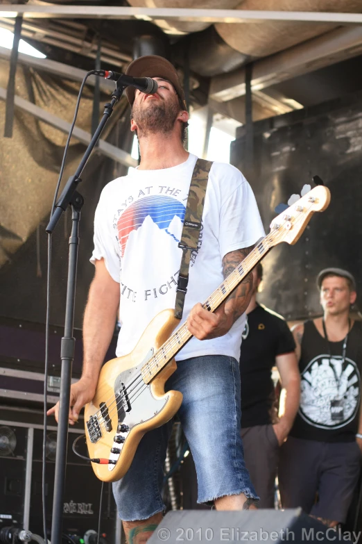 man playing guitar in front of microphone on stage