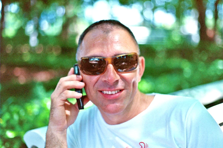 a man is smiling and talking on his cell phone