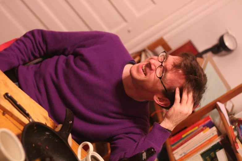 a man with glasses and a sweater making silly faces