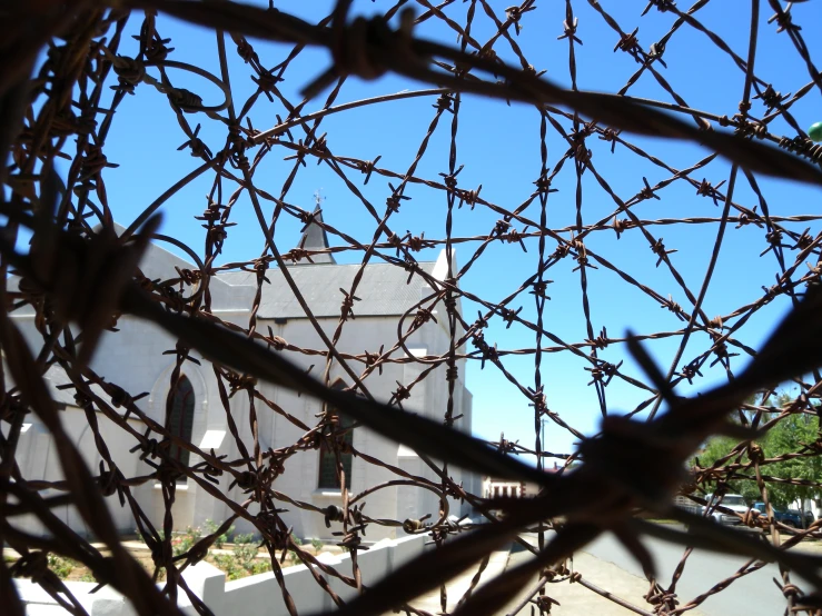 barbed wire surrounds the view of a white church building