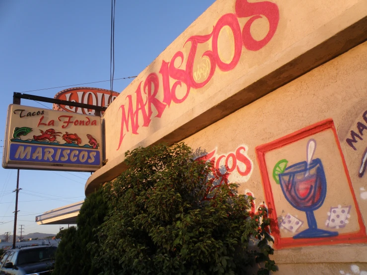 the side of a restaurant with a neon sign next to it