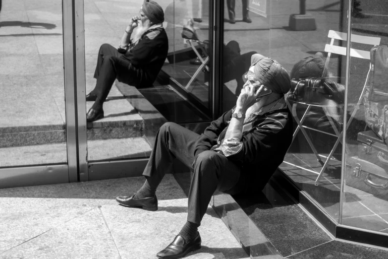 a man sits on a bench outside the glass wall and talks on his cellphone