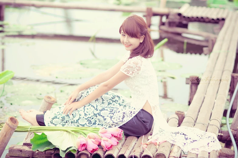 a woman sitting on top of a bamboo bridge