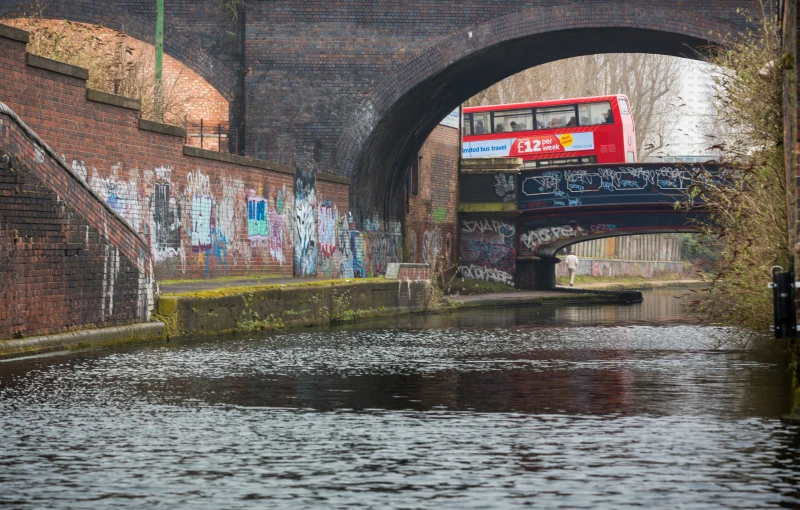 a double decker bus drives over an old bridge