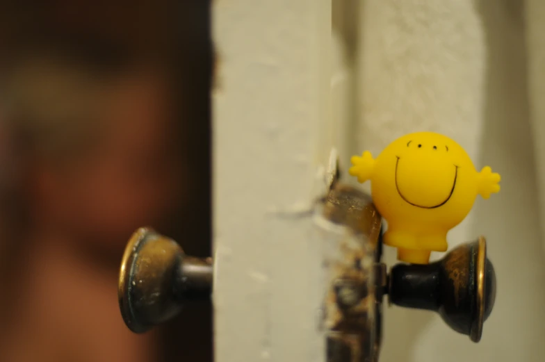 a small yellow rubber toy sitting on the door handle of a door