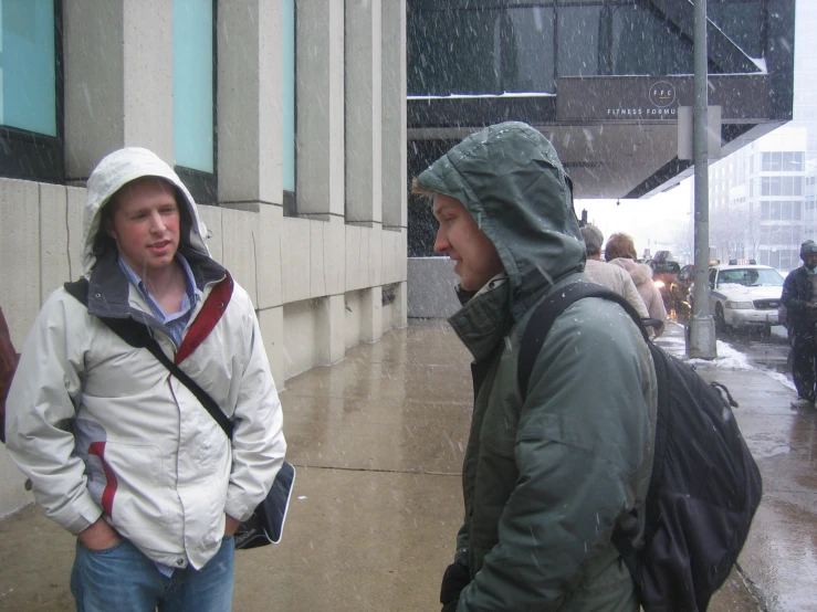 a couple of men are on a street in the rain