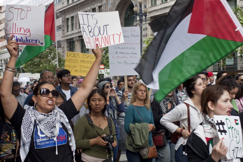 many people standing in a street holding signs