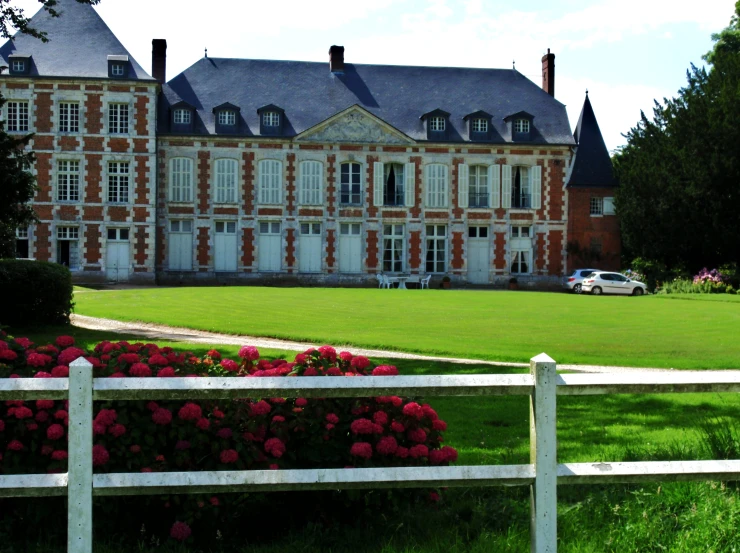 a big building with large front yard and a white fence