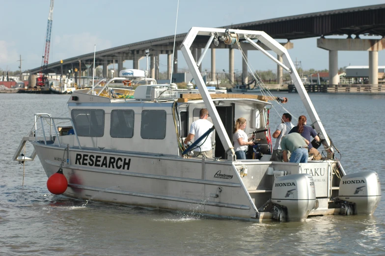 group of people sitting on the front of a boat under a bridge