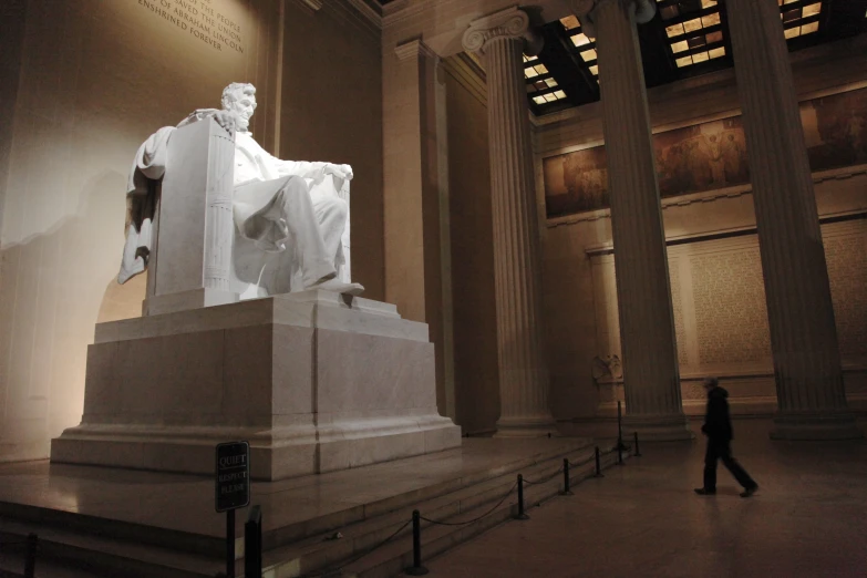 a woman walking through a large hall filled with statues