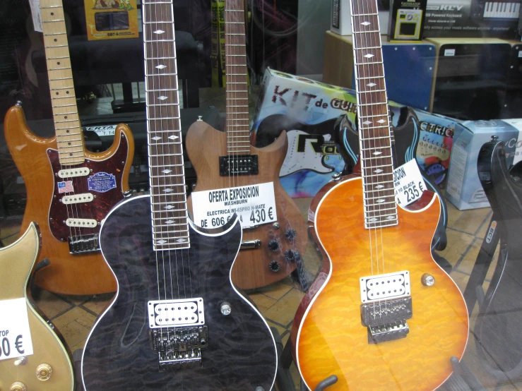 an array of guitars for sale sit inside a window